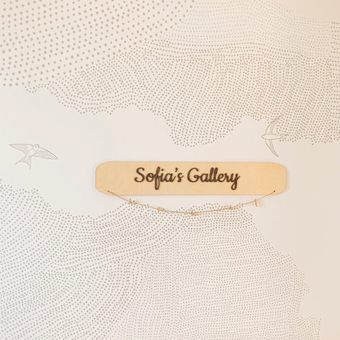 Wooden sign with 'Sofia's Gallery' on a textured beige background