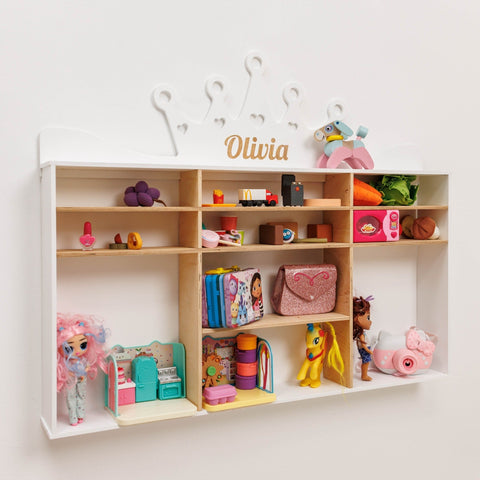 Children's toy shelf with various toys and a personalized name sign on a white wall.