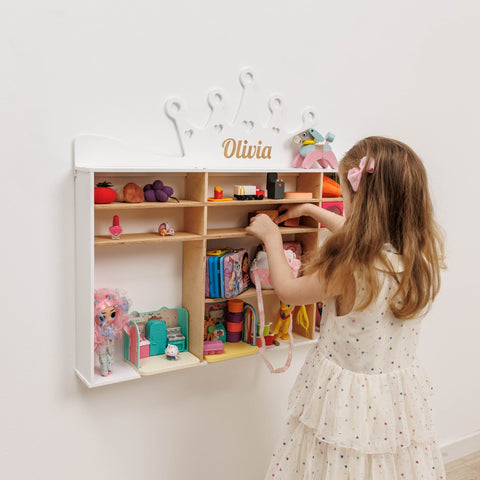Child playing with a toy shelf in a room with a white wall and a nameplate.