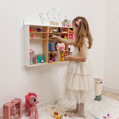 Young girl playing with toys in a room with a shelf and various items.
