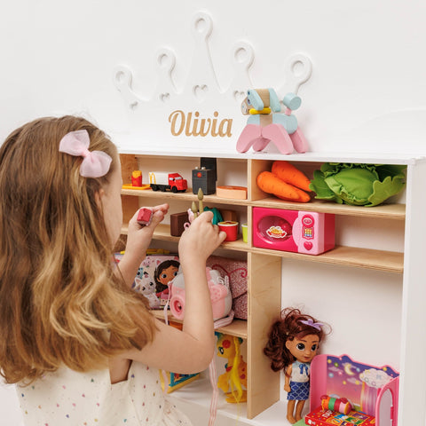 Child playing with a toy wardrobe filled with dolls and accessories