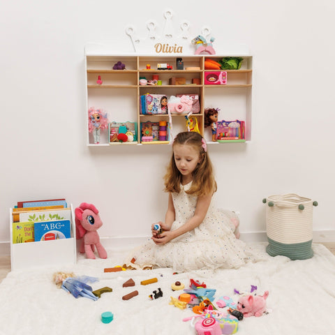 Young girl playing with toys in a room with a bookshelf and storage basket.