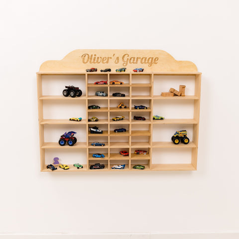 Wooden toy car display shelf with 'Oliver's Garage' on a white wall