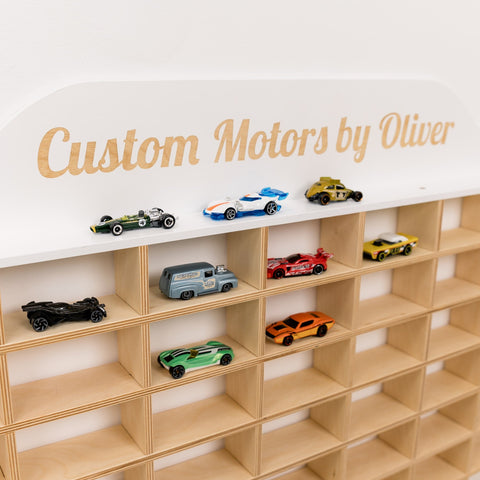 Wooden shelf with toy cars and a sign reading 'Custom Motors by Oliver' on a white background.