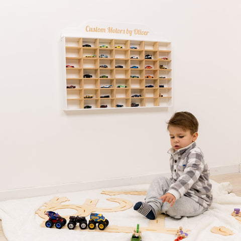 Child playing with toys in a room with a wooden toy car display.