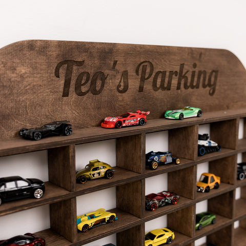 Wooden toy car parking area with 'Teo's Parking' engraving and various toy cars.